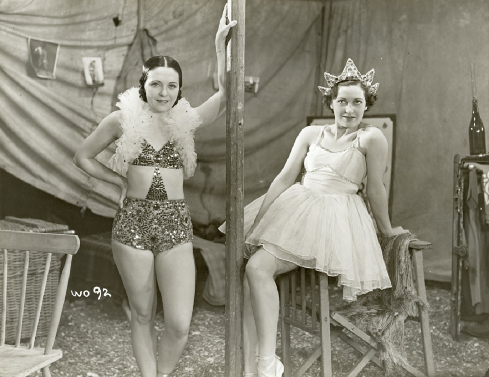 Two women is circus-type costumes inside a tent