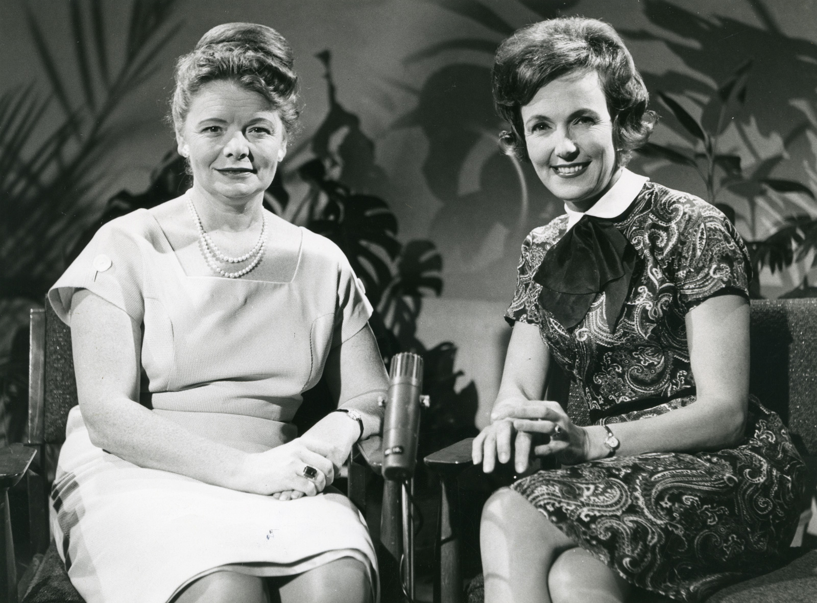 Two women seated and smiling directly at camera, c1956