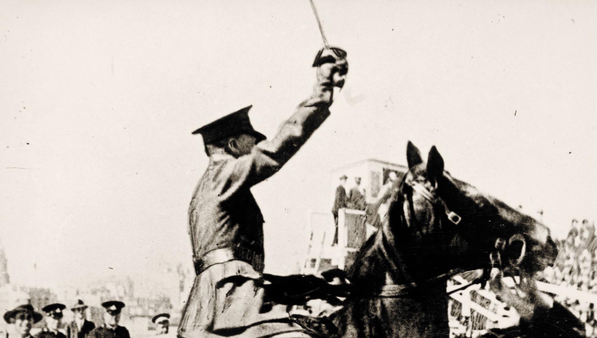 A still from a newsreel showing Major Francis De Groot on horseback with his sword aloft having just cut the ribbon of the Sydney Harbour Bridge.