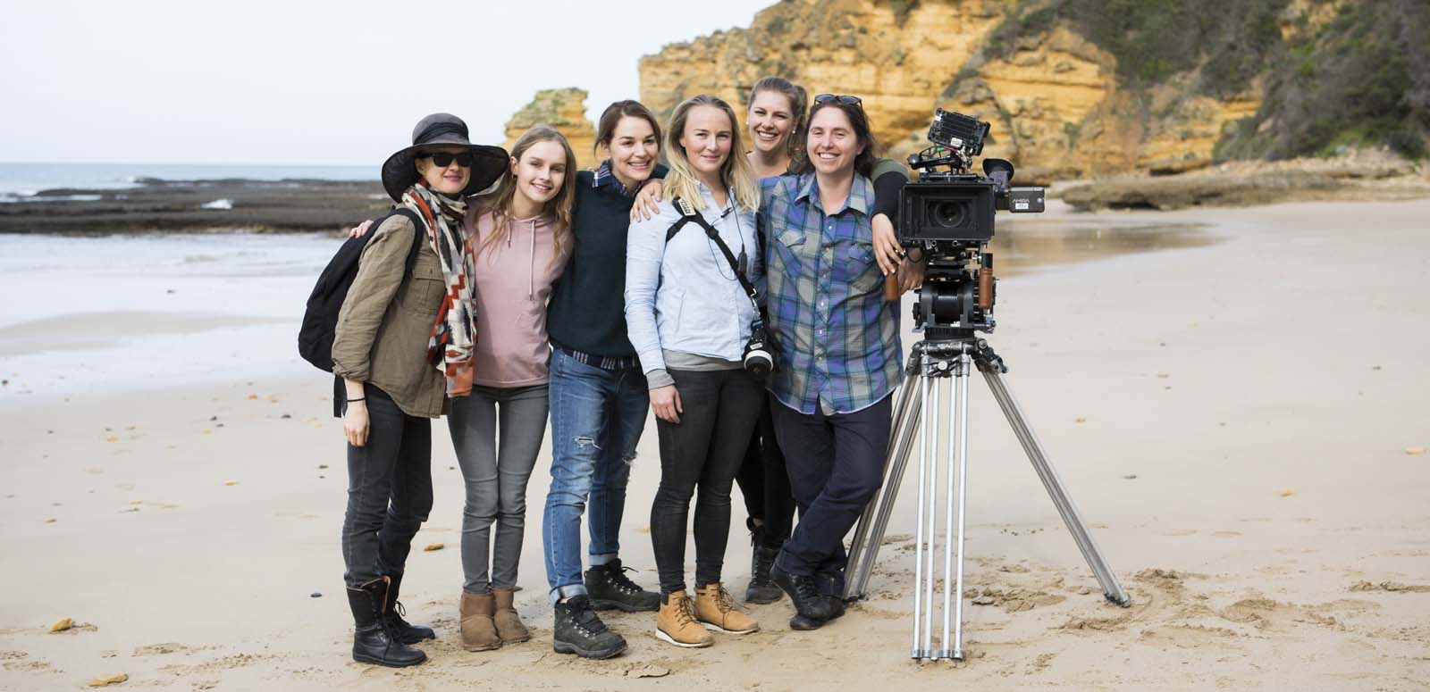 The female cast and camera crew of the film Undertow pose on a beach with a film camera during production