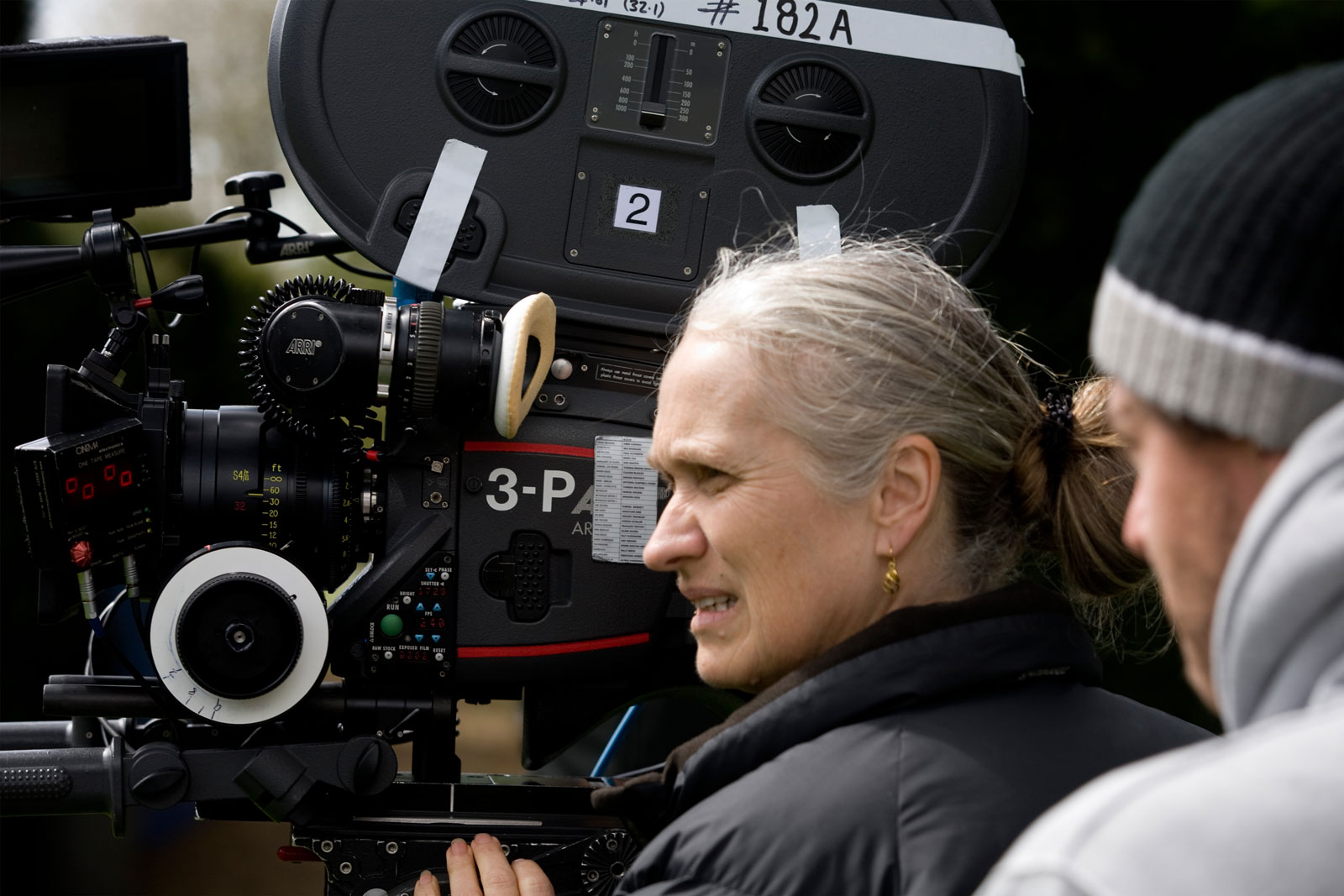 Director Jane Campion, in profile, standing near a film camera on set.
