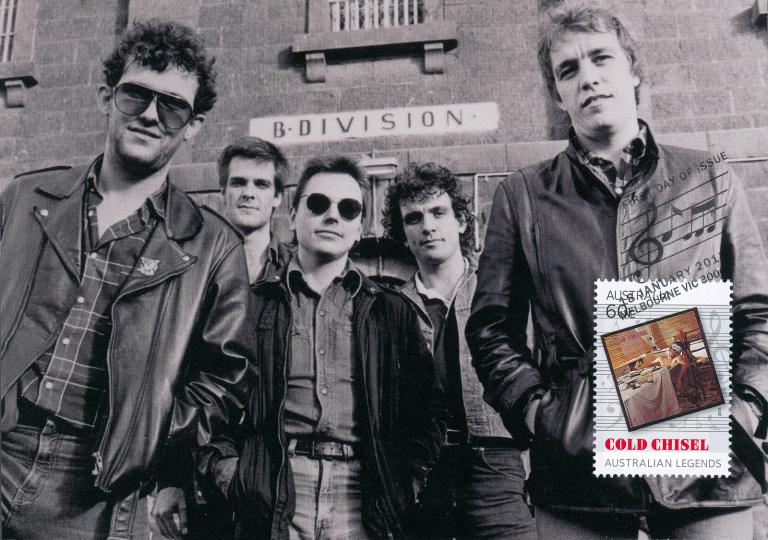Members of the Australian Rock band Cold Chisel, from left to right - Jimmy Barnes, Don Walker, Phil Small, Ian Moss and Steve Prestwich, standing looking down at an angle at the camera. There's also an inset image of a postage stamp featuring the band. 