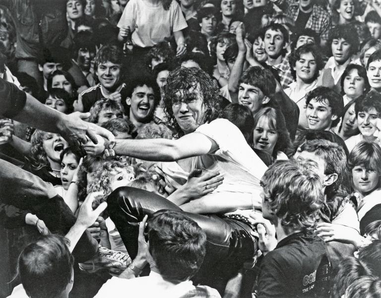 Cold Chisel lead singer Jimmy Barnes in among the crowd at a concert. Hands can be seen reaching out to pull him back on the stage.