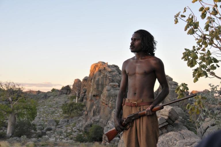 A young man holding a rifle in the Australian outback.