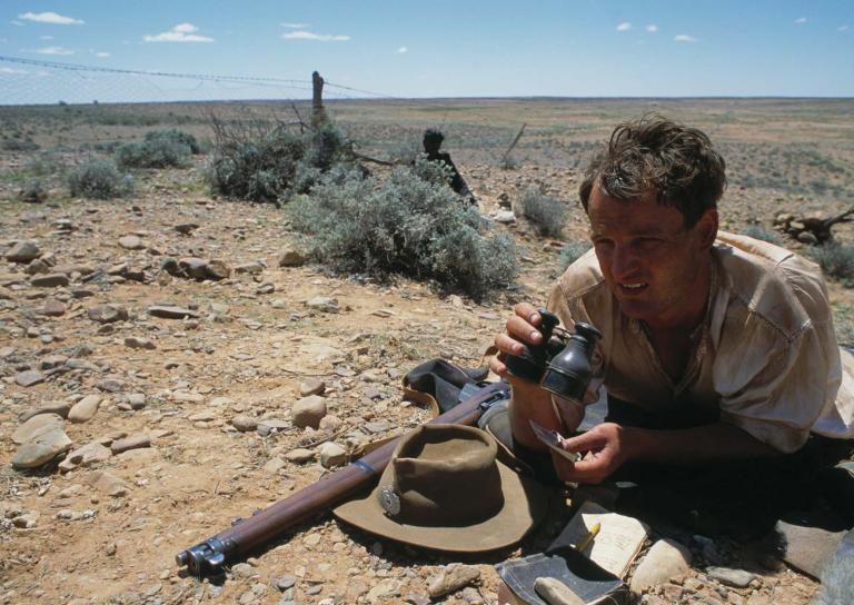 Jason Clarke lies by the rabbit-proof fence looking for the escaped girls in a still from the film Rabbit-Proof Fence.