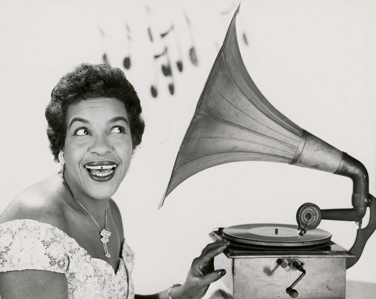 Publicity shot of Winifred Atwell listening to an old gramophone