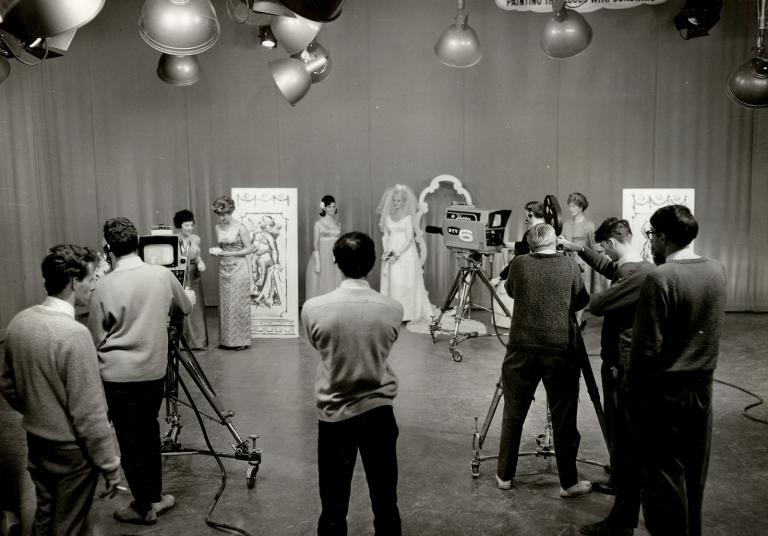 Filming a television show in a studio, 1960s. A woman in the centre of the set is wearing a wedding dress. 