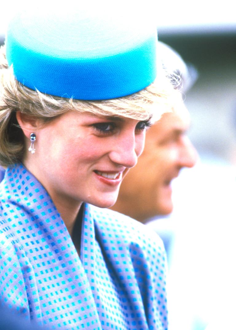 Close-up of Princess Diana in Australia in 1988 wearing blue dress and blue pill-box hat, with Prime Minister Bob Hawke in the background.