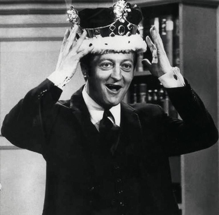 Graham Kennedy standing and holding the crown on his head