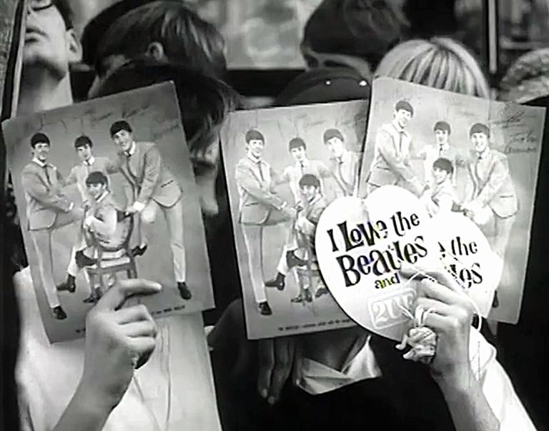 Fans in Sydney hold up photos and heart-shaped cards as they wait for The Beatles arrival at the Sheraton hotel.