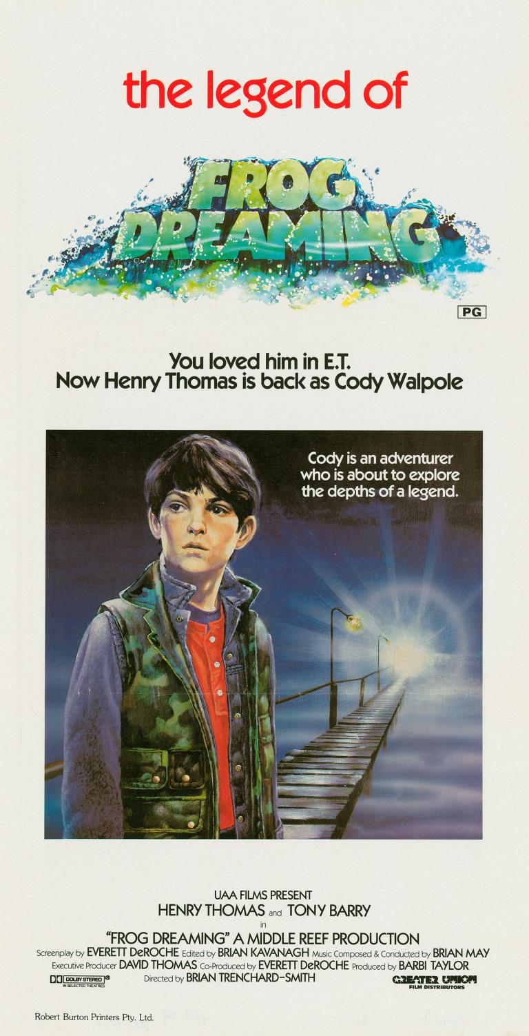 Poster art for a film called 'the legend of frog dreaming' showing a young boy wearing a camouflage vest standing on a platform or pier with a light shining in the distance. The film title and credits are above and below the image.