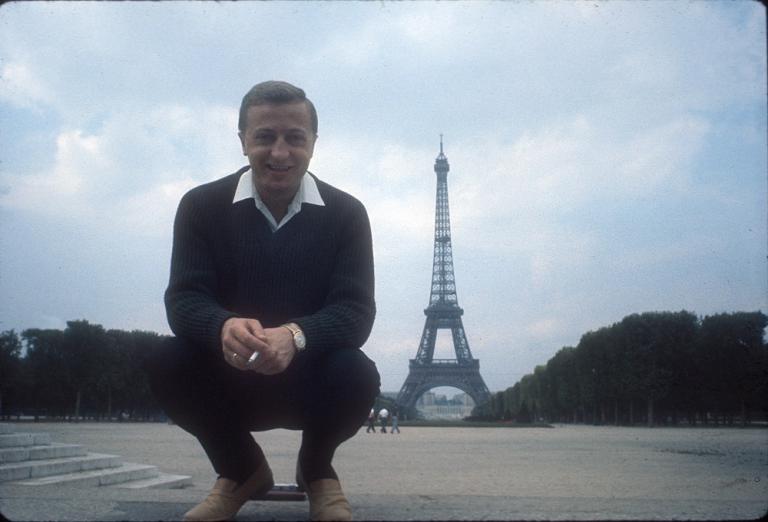 Graham Kennedy crouches looking into the camera with the Eiffel Tower in the background