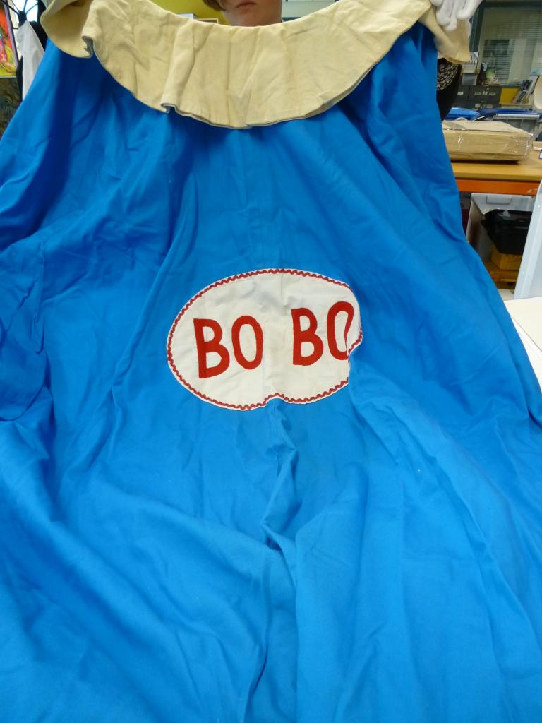 Blue clown cape with white fringe and white oval in centre with Bobo stitched in red letters