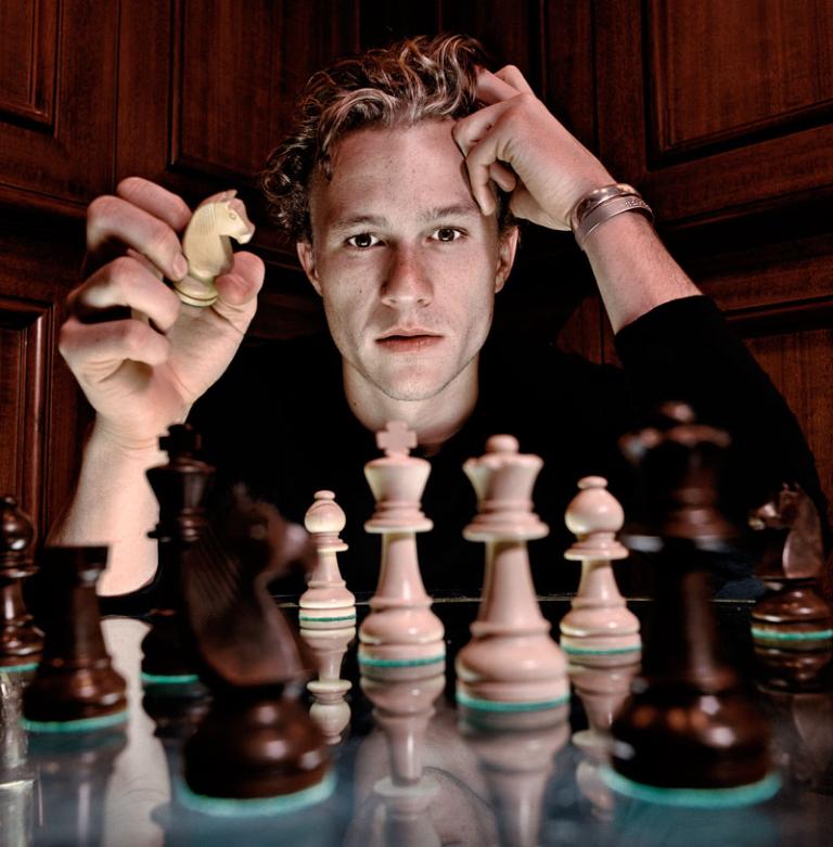 Portrait of Heath Ledger sitting behind a chess board.
