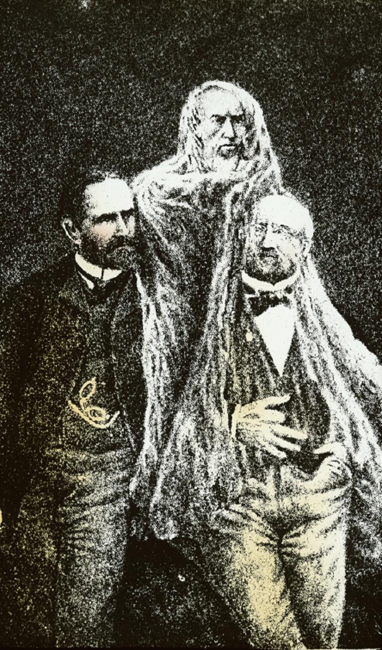 Colour glass slide showing two men standing together, a spirit in white robes hovering between and through them