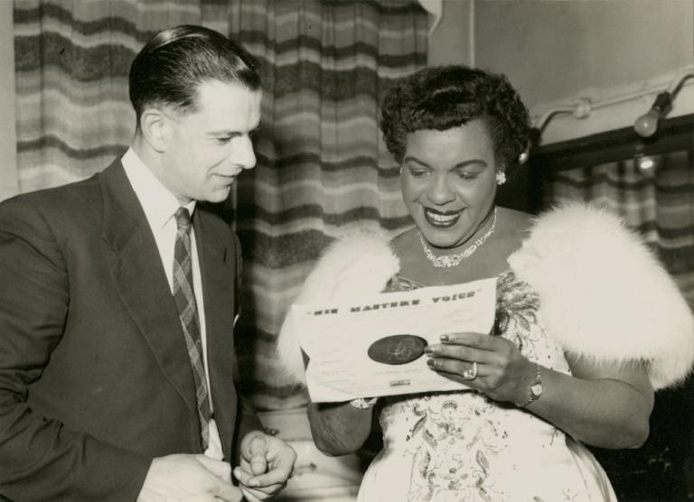 Winifred Atwell autographing a record sleeve for a clean cut looking man