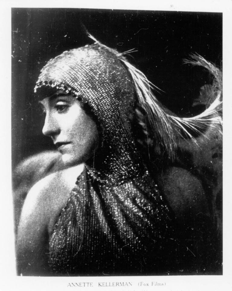 A black and white head shot of Annette Kellerman, wearing a sequinned costume with feathers as part of the head-dress.
