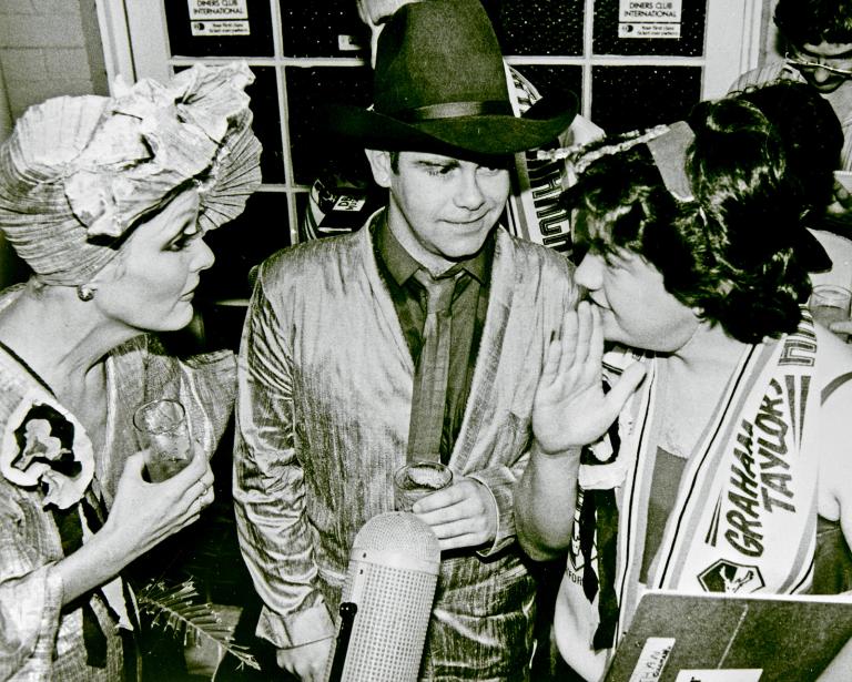From left to right, entertainer Jeanne Little, singer Elton John and Wonder World! reporter Jonathan Coleman, circa 1982 in what looks to be a press conference.