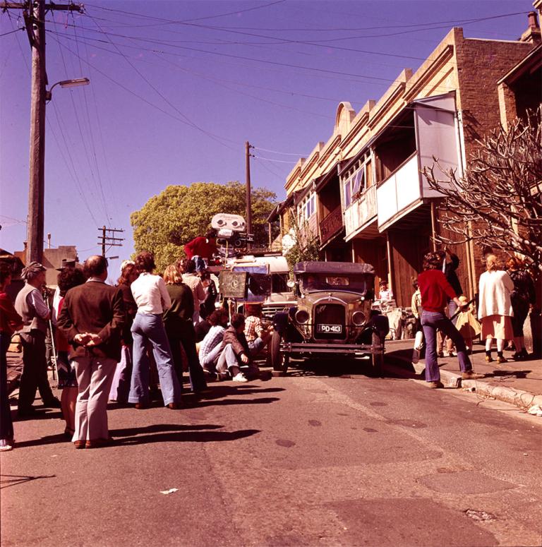 Crew filming vintage car in front of a terrace house on the streets of Sydney for Caddie, 1976