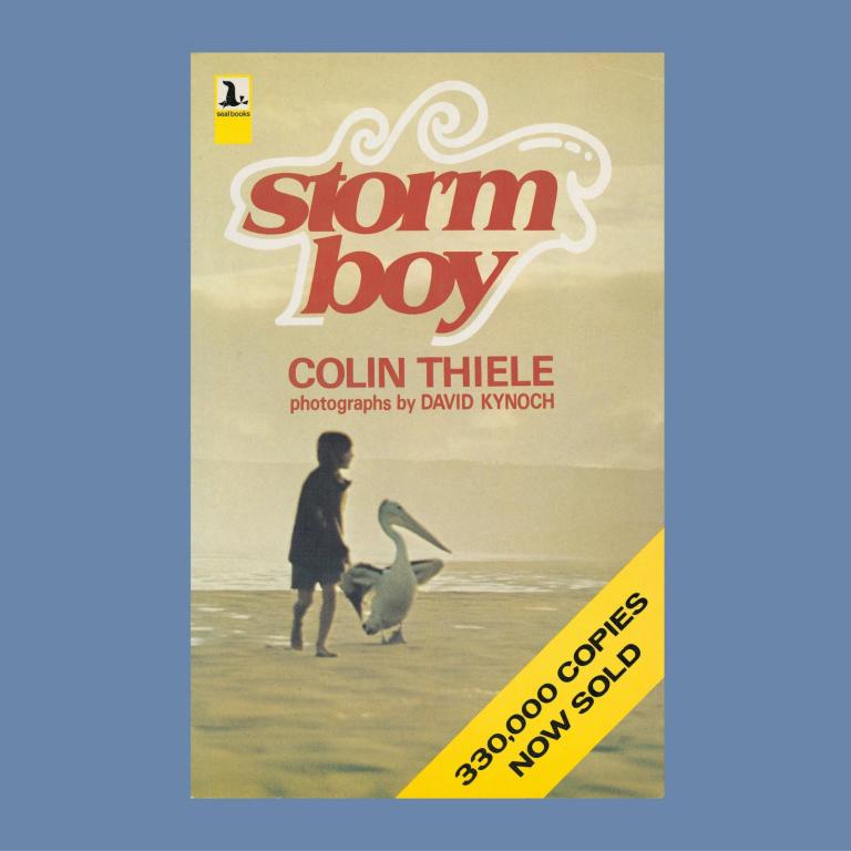 Cover of the book Storm Boy by Colin Thiele featuring a still from the film of Greg Rowe and Mr Percival the pelican walking along the beach. A banner saying '330,000 copies now sold' is on the corner of the cover.