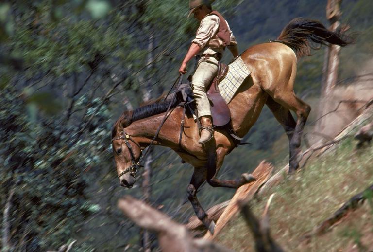 A man rides a horse down a perilous slope