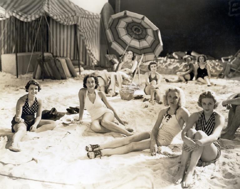 A group of people lounging on a film set made to look like a beach.