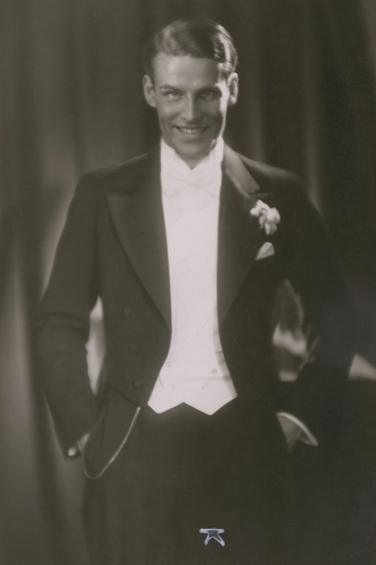 Actor Helmuth Kionka, dressed in a black tuxedo with white bow tie, smiles at the camera. 