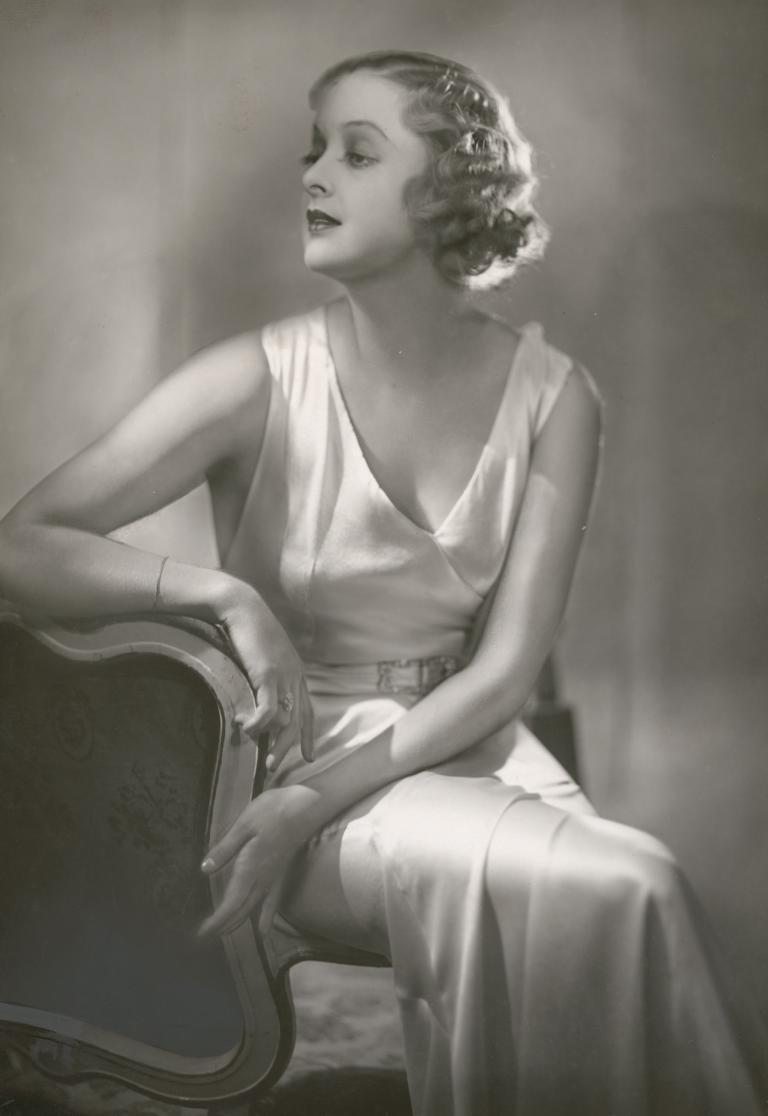 Photographic portrait of film actress Lilian Ellis, seated with her head turned away from the camera.