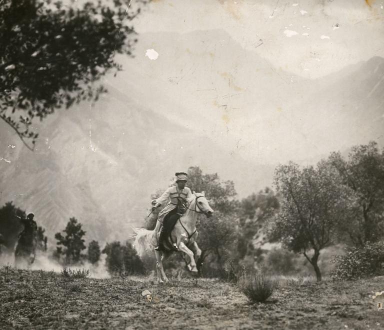 A soldier rides a white horse, against a backdrop of mountains, in a still from the film The White Devil, 1930.