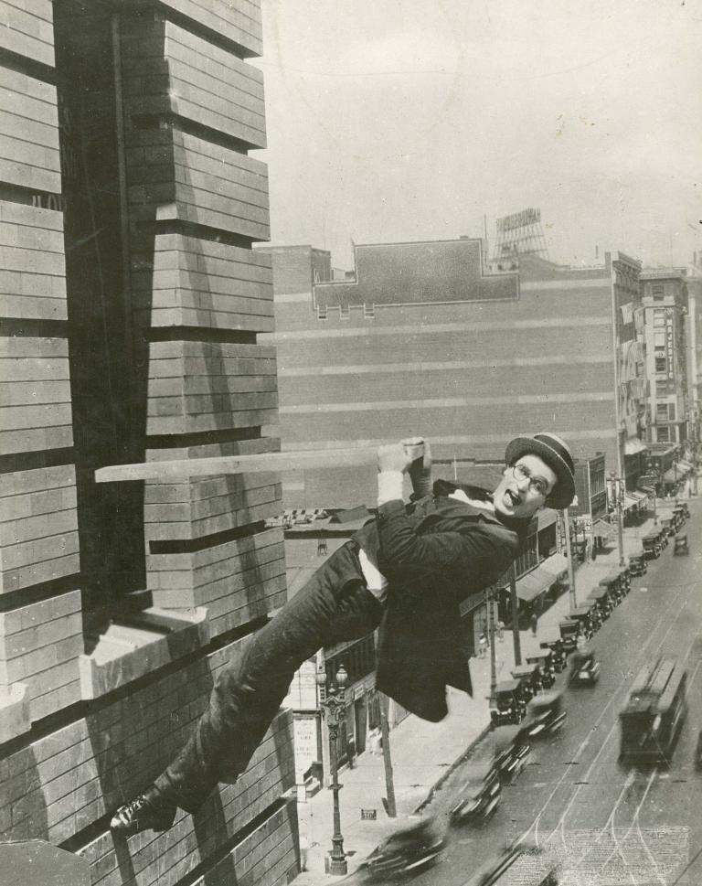 Harold Lloyd hangs off a building above a busy street in a scene from the 1923 film Safety Last!