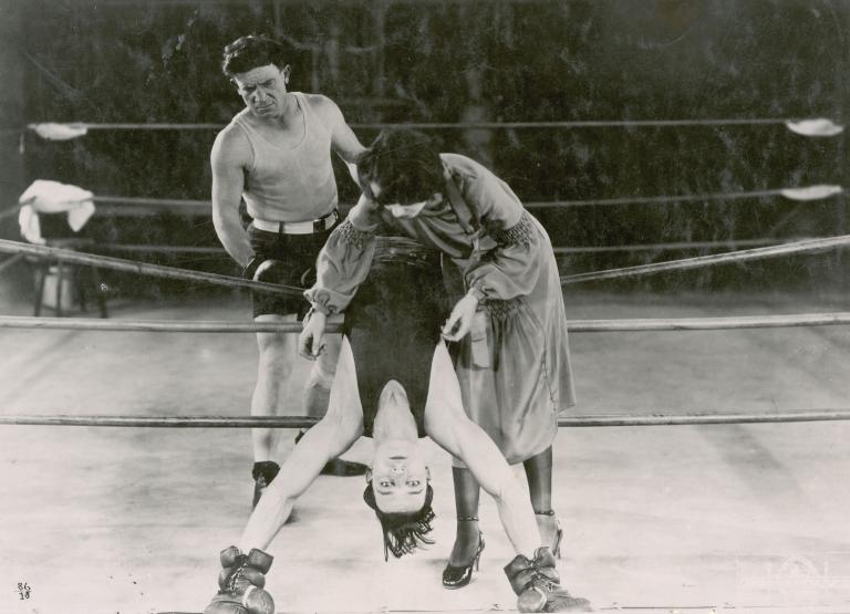 Buster Keaton leans backwards over the ropes in a boxing ring in a still from Battling Butler, 1926.
