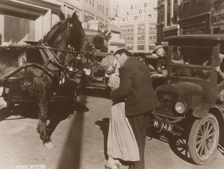A young couple embrace on a busy street in a still from the film Sunrise, 1927.