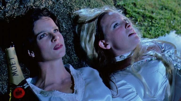 Rhonda (Rachel Griffiths) and Muriel (Toni Collette) laying on the grass in ABBA costumes staring at the sky