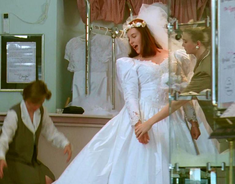 Muriel (Toni Collette) trying on a wedding dress in a bridal shop
