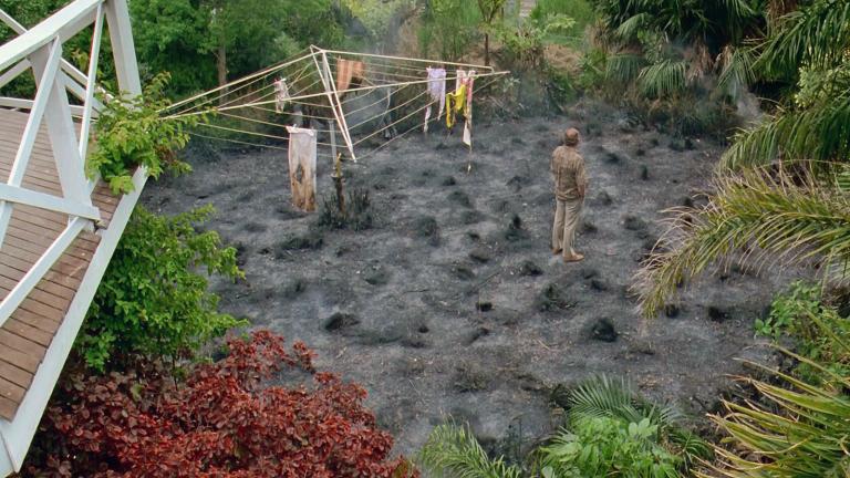 Bill (Bill Hunter) standing in the backyard where Betty (Jeanie Drynan) has lit a fire