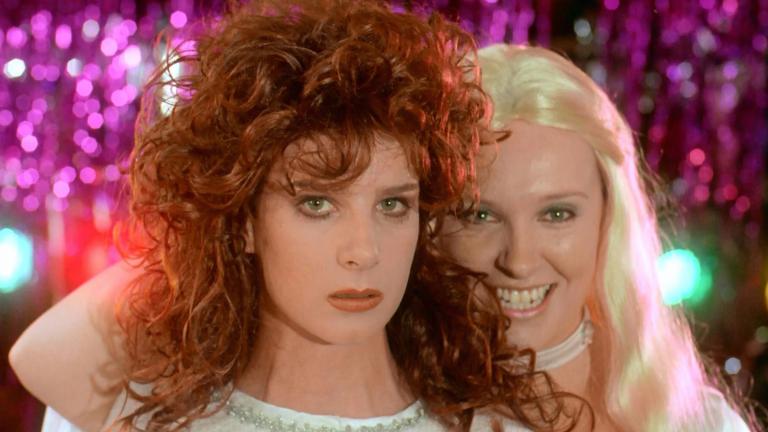 Muriel (Toni Collette) smiling behind Rhonda (Rachel Griffiths) looking sombre as the ABBA girls