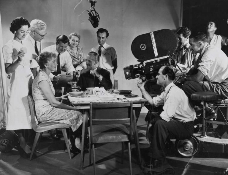 Cast and crew of ten people are filming in a production studio.