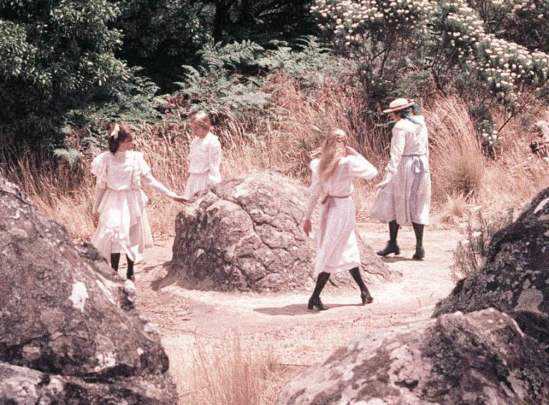 The four schoolgirls walk in a circle around a rock