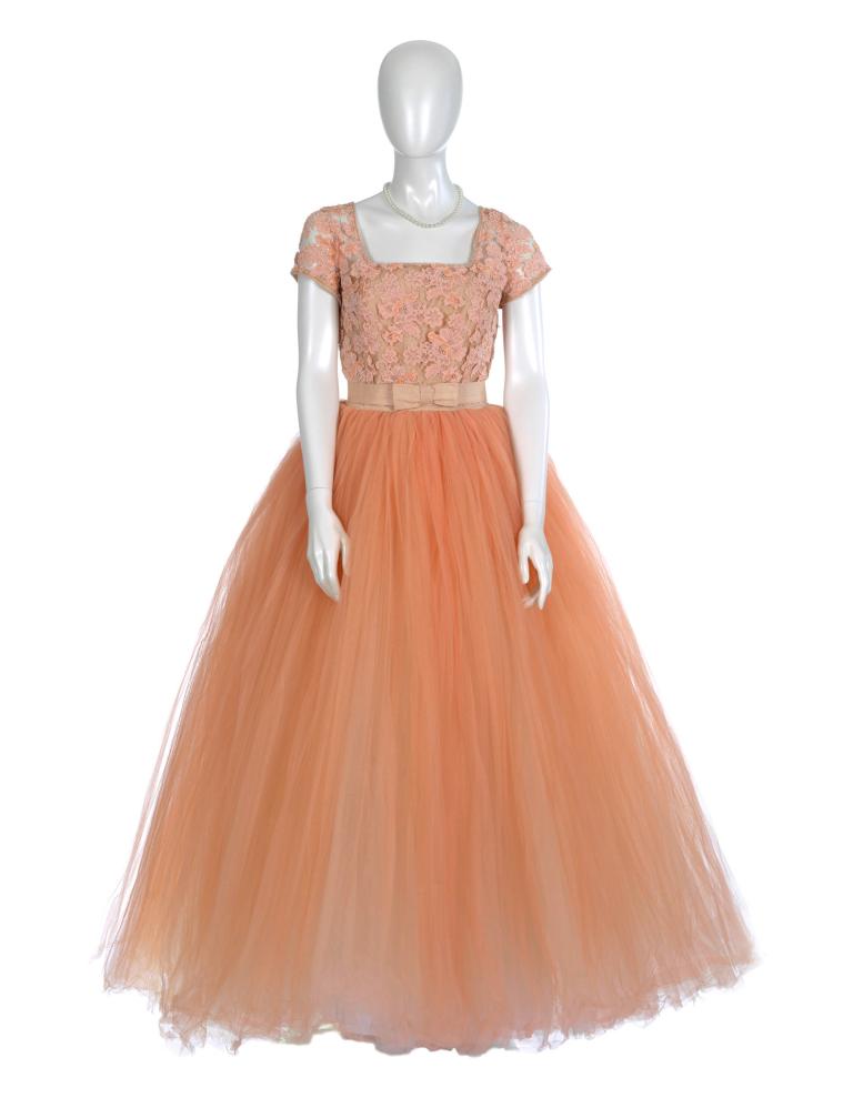 peach-coloured, floor-length frock with tulle skirt and lace bodice and floral hairpiece.