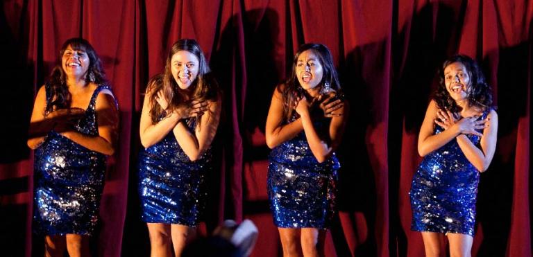 The four women who play The Sapphires in the feature film in blue dresses with arms crossed over their chests