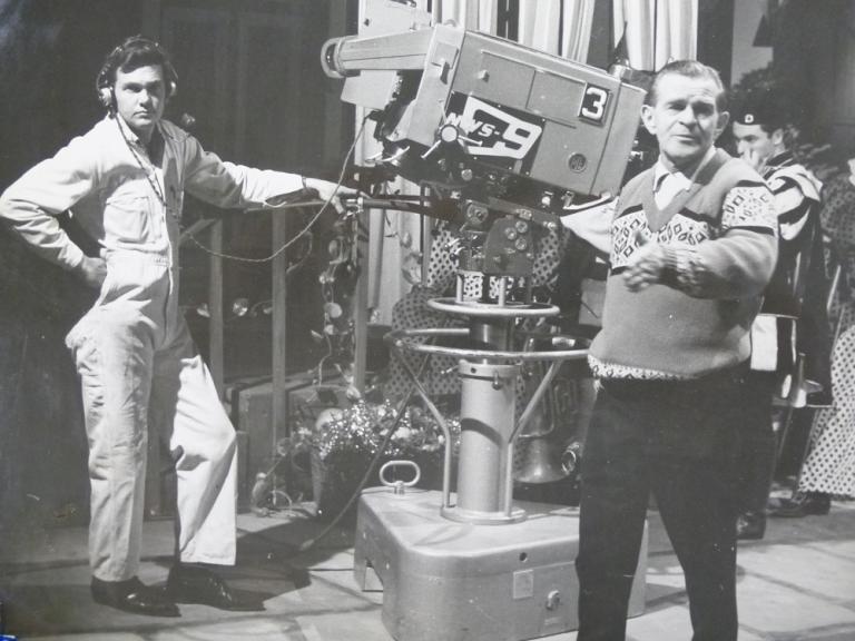 Television studio shot of Hal Turner standing next to a TV camera and operator directing a production.