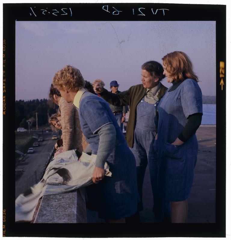 Actresses Betty Bobbitt and Val Lehman rehearsing the rooftop protest scene.  An extra is holding a sign, leaning slightly over the ledge.