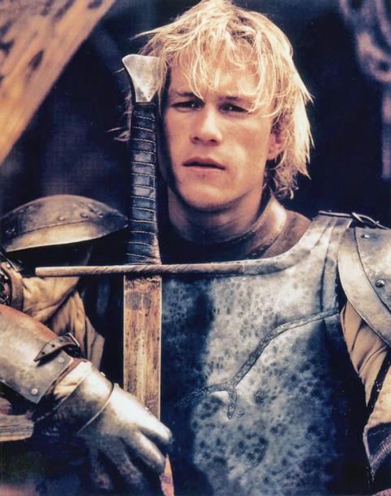 Heath Ledger in a publicity portrait of him as William Thatcher wearing an armour plate and leaning on a sword.