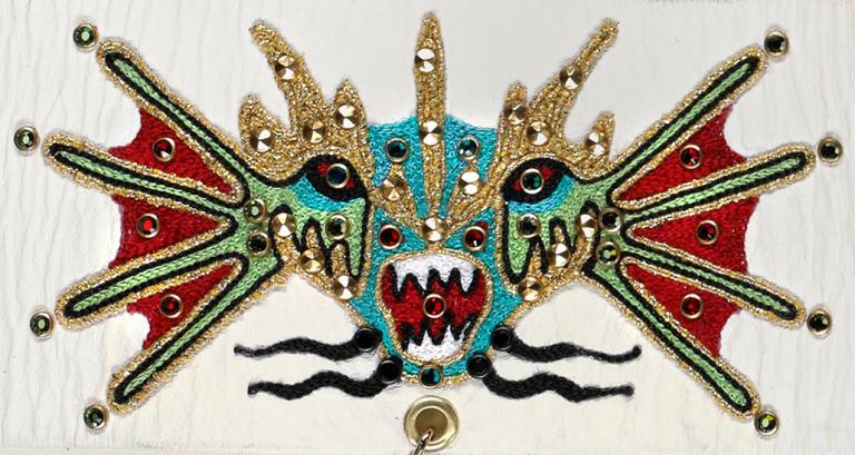 Close up of an embroidered image of the head of a Chinese dragon. 