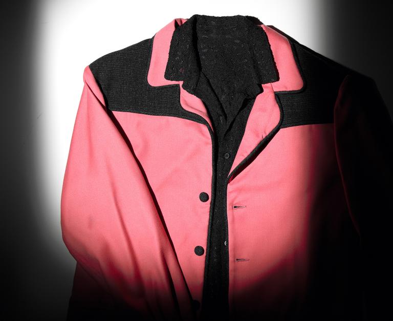 Candy-pink-coloured jacket with black trim on the shoulders and black buttons. 