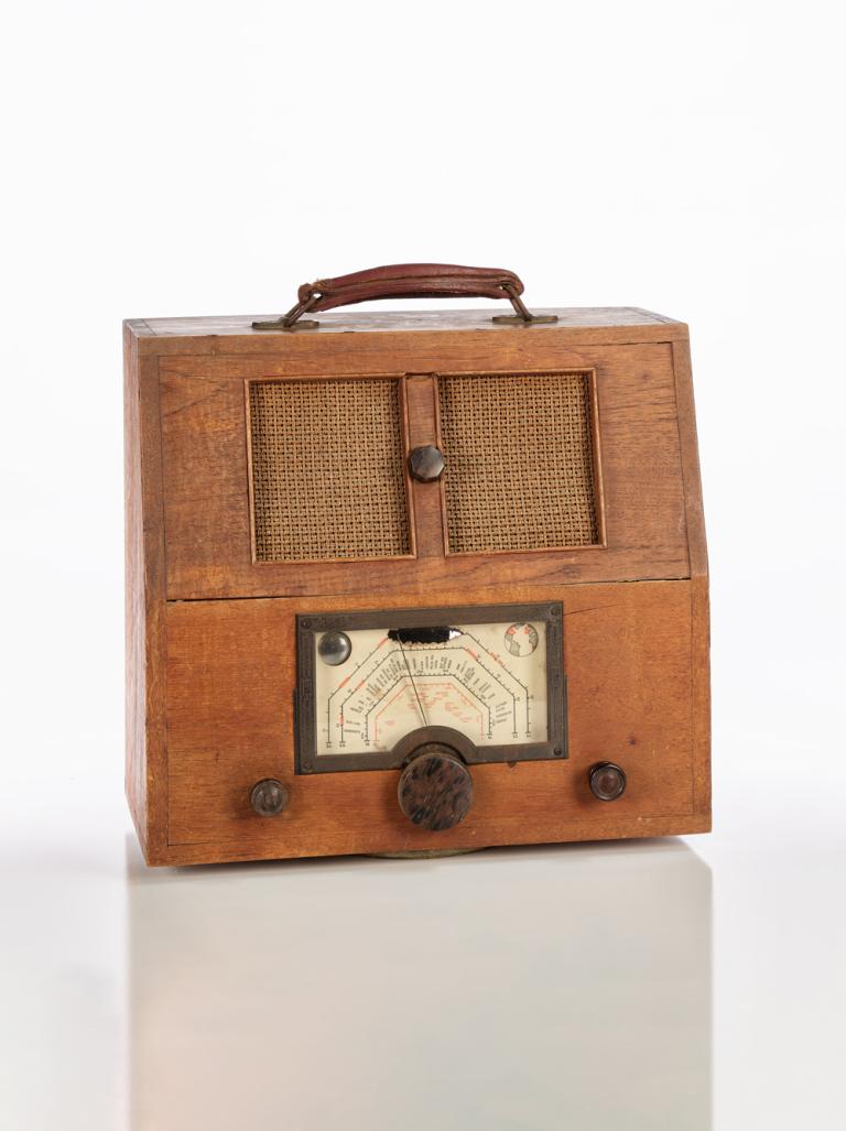 A homemade radio with a dial and speakers on the front and a handle on top. C1936