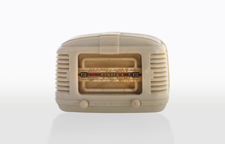 Portable console or mantle radio in a cream-coloured plastic housing with dials on the front.