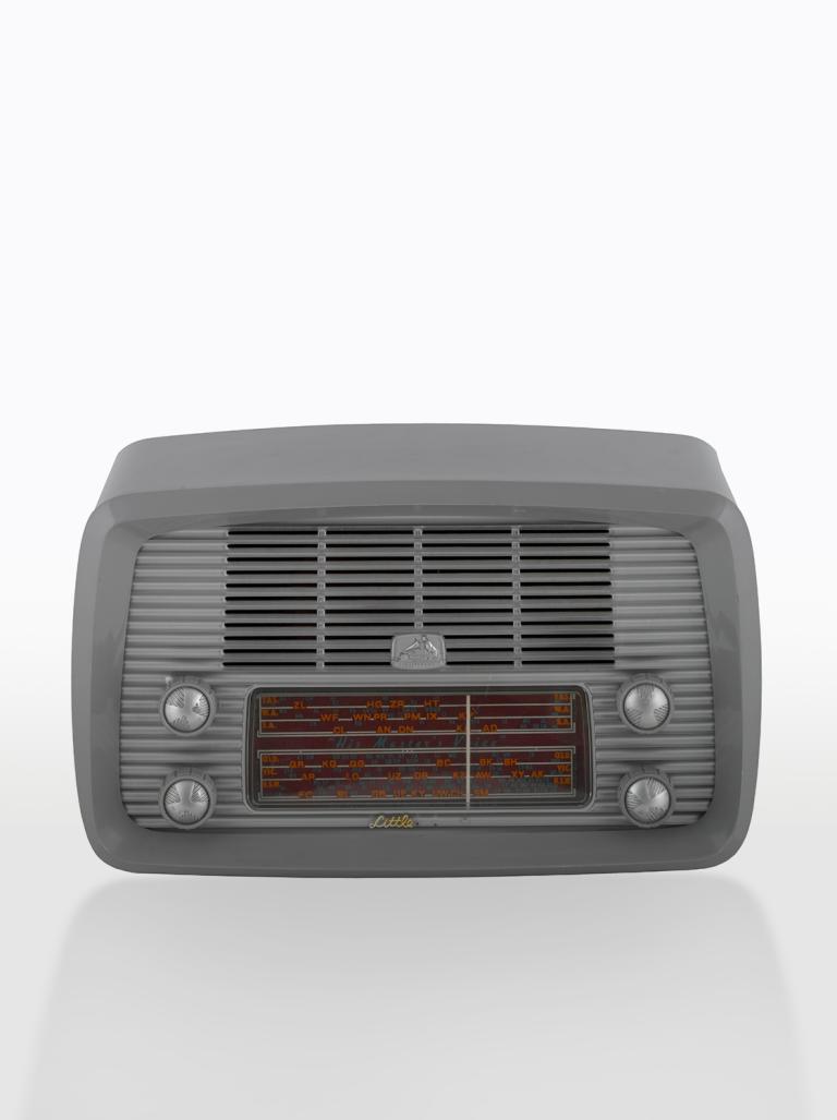 A boxy-shaped HMV radio receiver from 1949. It is in a grey, plastic housing with dials, frequency display and speaker on the front. 