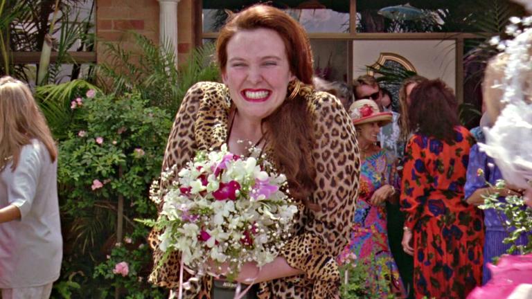 Muriel (Toni Collette) holding a bouquet and smiling broadly