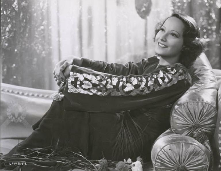 Publicity portrait of Merle Oberon reclining on a chaise lounge